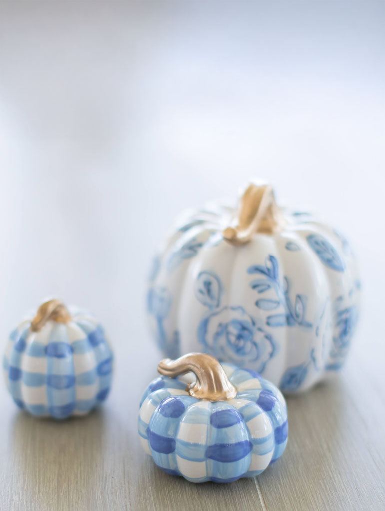 Three decorative pumpkins with blue and white patterns on a light wooden surface.